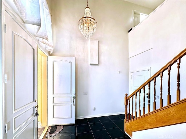 foyer with dark tile patterned floors, baseboards, stairway, a high ceiling, and a notable chandelier