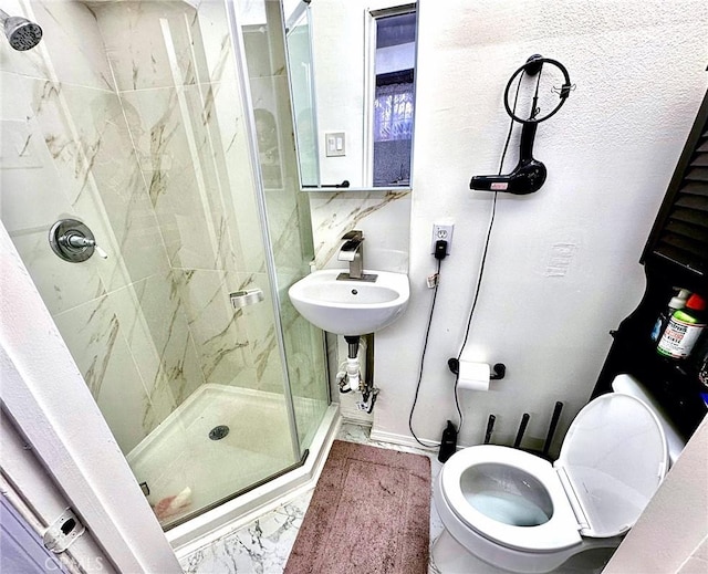 bathroom with toilet, marble finish floor, a stall shower, and a sink