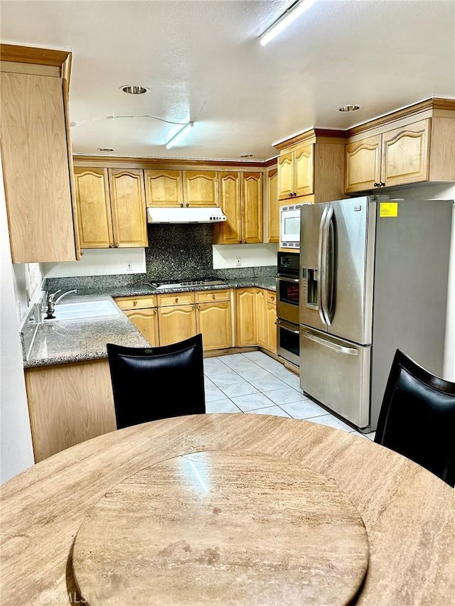 kitchen with a sink, under cabinet range hood, and appliances with stainless steel finishes