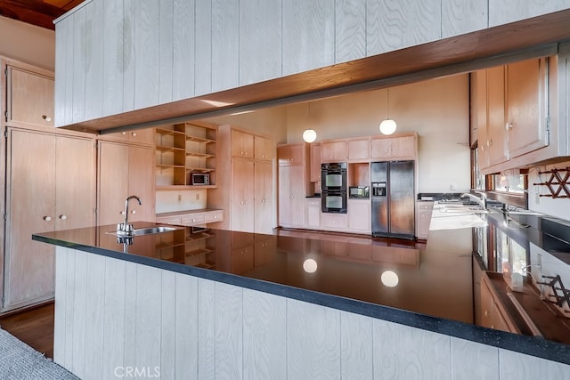 kitchen with hanging light fixtures, a peninsula, light brown cabinetry, black appliances, and a sink