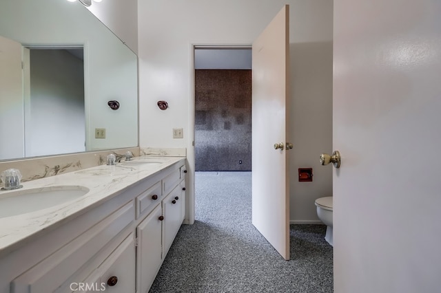 full bathroom with double vanity, a sink, and toilet