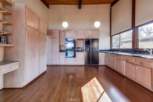 kitchen featuring dark countertops, a sink, black appliances, pendant lighting, and beam ceiling