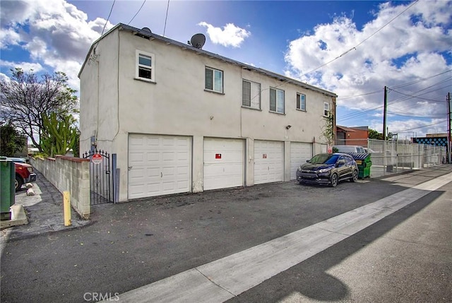 back of house with fence, stucco siding, and an attached garage