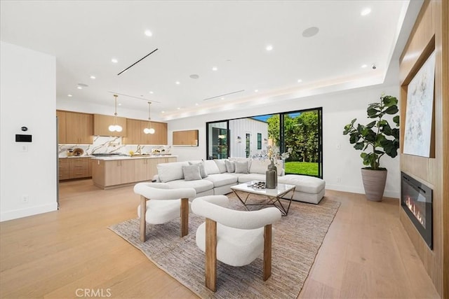 living room featuring baseboards, a fireplace, light wood-style flooring, and recessed lighting