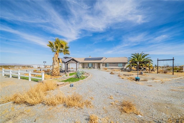 view of front of property with roof mounted solar panels and fence