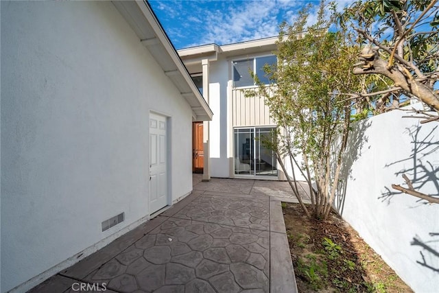 rear view of property featuring crawl space, a patio area, fence, and stucco siding