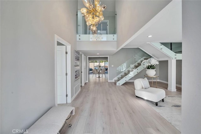 entryway featuring baseboards, a towering ceiling, wood finished floors, an inviting chandelier, and stairs