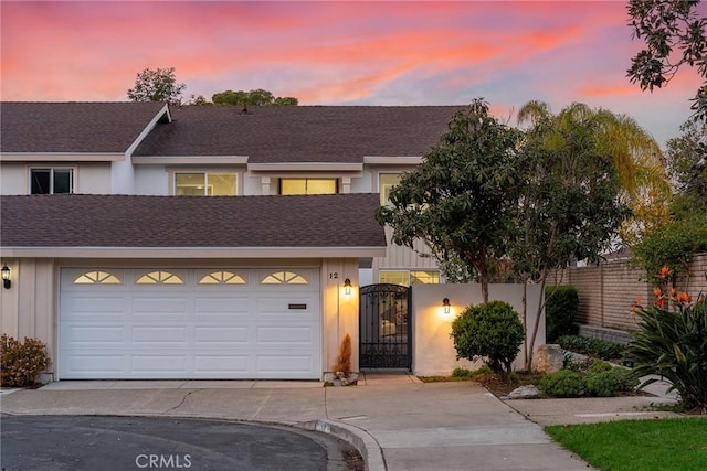 townhome / multi-family property with a shingled roof, fence, concrete driveway, a gate, and board and batten siding