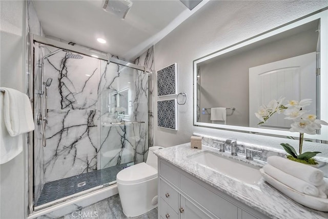 bathroom featuring a marble finish shower, vanity, and toilet