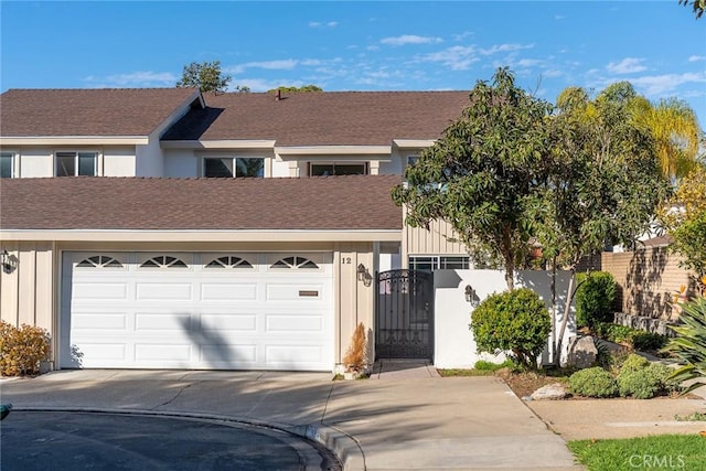 view of front of home featuring roof with shingles, concrete driveway, an attached garage, a gate, and fence