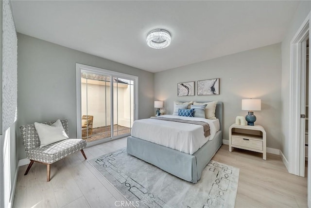 bedroom featuring baseboards, light wood-style flooring, and access to exterior