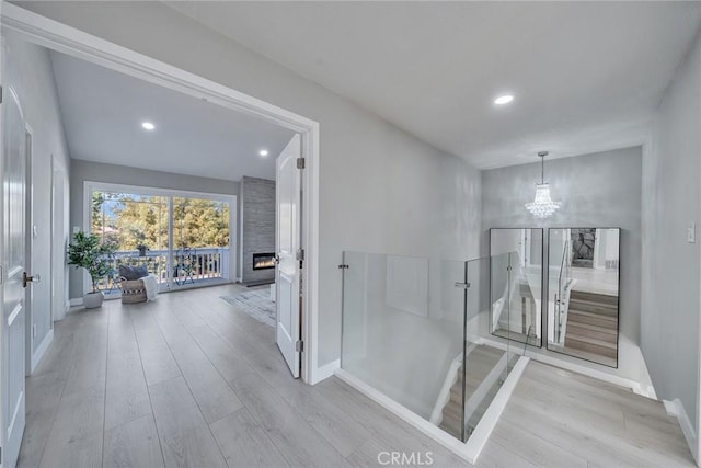 hallway with recessed lighting, a chandelier, wood finished floors, and an upstairs landing