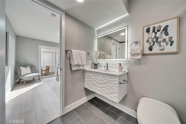 bathroom featuring toilet, vanity, and baseboards