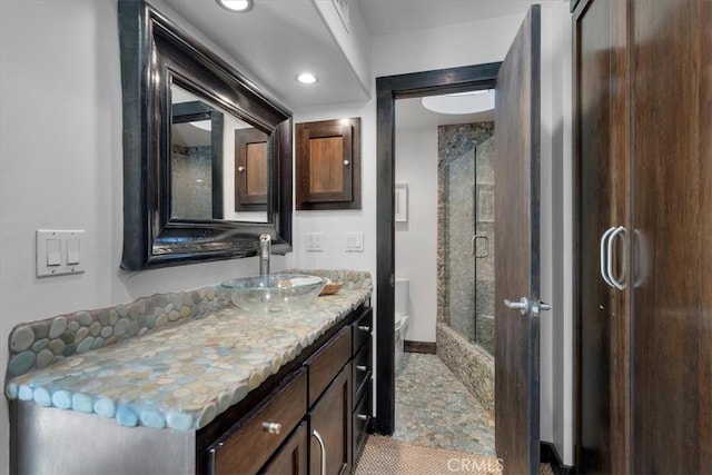 bathroom featuring a shower with door, recessed lighting, toilet, vanity, and baseboards