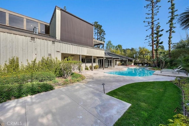 outdoor pool featuring a patio and a lawn