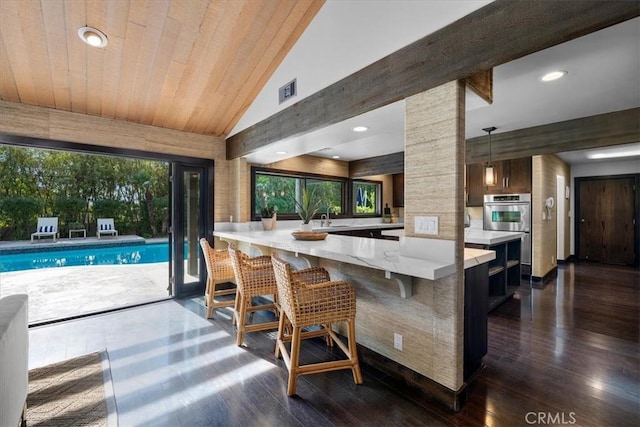 kitchen with vaulted ceiling with beams, a peninsula, a breakfast bar, and decorative light fixtures