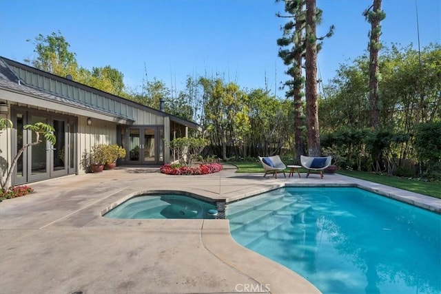 view of swimming pool featuring a pool with connected hot tub, a patio, and french doors