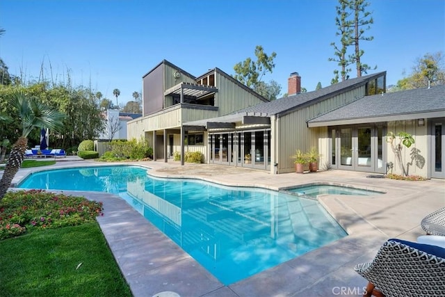 view of swimming pool with a pool with connected hot tub, a patio, and french doors