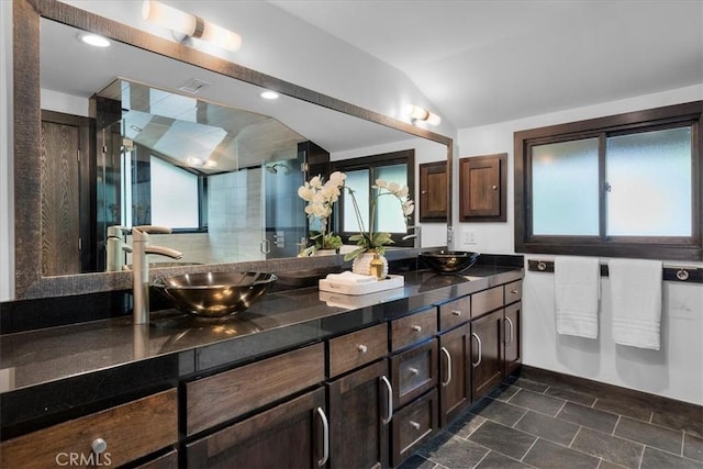 full bathroom featuring lofted ceiling, a shower stall, double vanity, and a sink