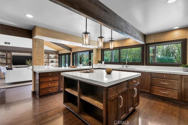 kitchen with light countertops, a sink, a center island with sink, and decorative light fixtures