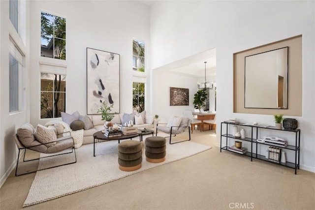 living area with a chandelier, baseboards, carpet flooring, and a high ceiling