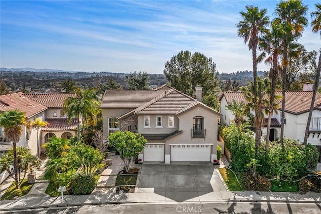 mediterranean / spanish-style home featuring concrete driveway, a tiled roof, an attached garage, and stucco siding