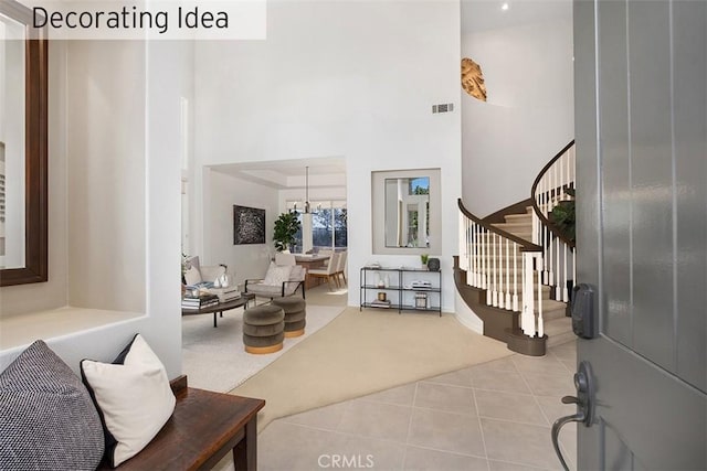 carpeted entryway featuring tile patterned flooring, a notable chandelier, a towering ceiling, visible vents, and stairs