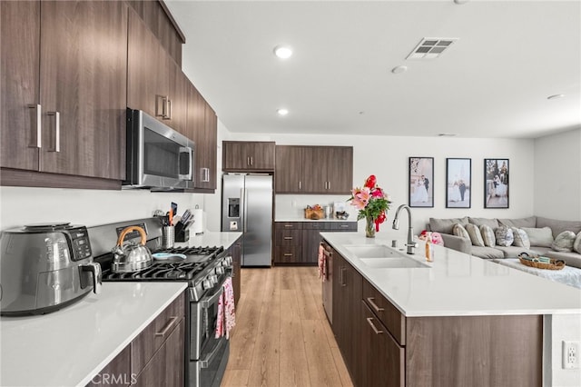 kitchen featuring a sink, visible vents, open floor plan, light countertops, and appliances with stainless steel finishes