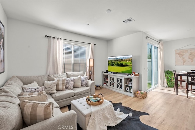 living room featuring a healthy amount of sunlight, light wood-style floors, and visible vents