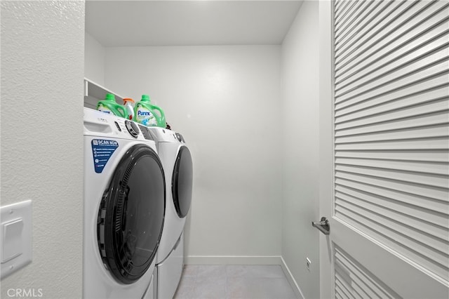 laundry room with laundry area, baseboards, washer and dryer, and light tile patterned flooring