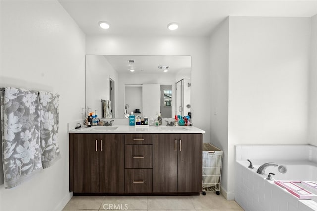 bathroom featuring a bath, tile patterned flooring, double vanity, and a sink