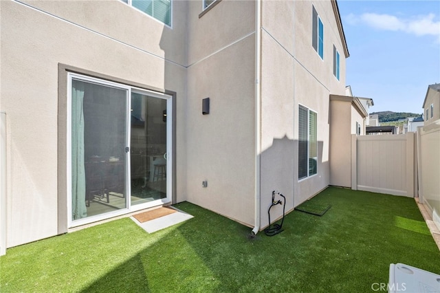 exterior space with fence, a lawn, and stucco siding