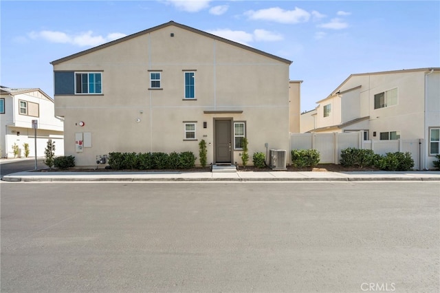 view of front of house with fence, central AC unit, and stucco siding