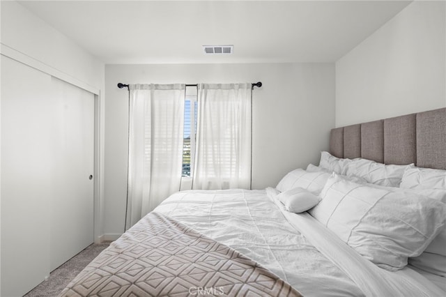 bedroom featuring a closet, visible vents, and light colored carpet