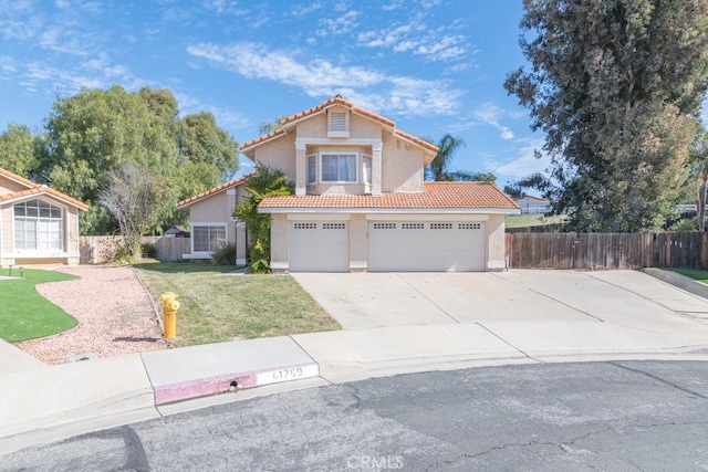 mediterranean / spanish house featuring a tile roof, stucco siding, fence, driveway, and a front lawn