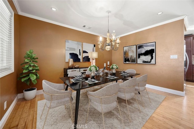 dining room with baseboards, light wood finished floors, and crown molding