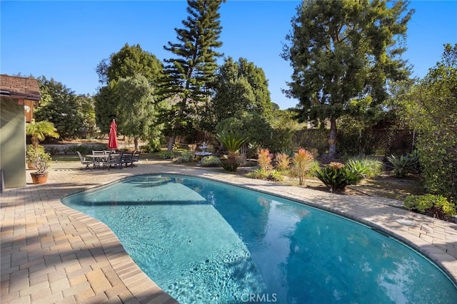 pool with outdoor dining space, a patio area, and a fenced backyard