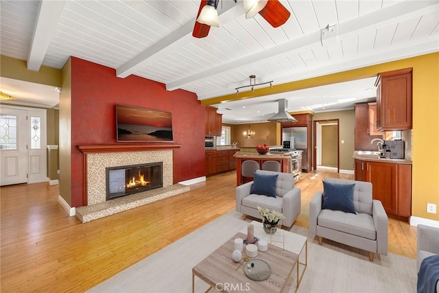 living room featuring a wealth of natural light, beamed ceiling, and light wood finished floors