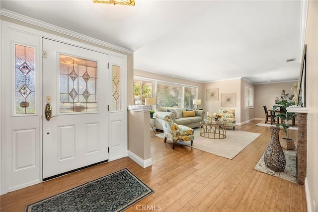 foyer entrance featuring visible vents, baseboards, crown molding, and hardwood / wood-style flooring