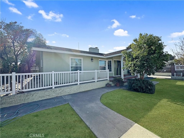 ranch-style house with a front yard, fence, and stucco siding