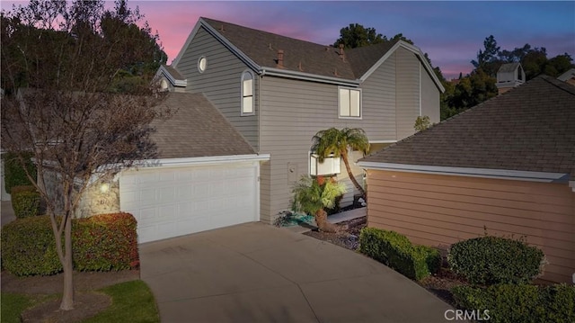 exterior space with a garage, concrete driveway, and roof with shingles