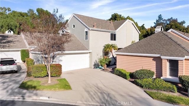 traditional-style home with driveway, a shingled roof, and a garage