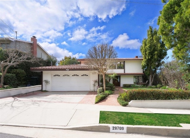 view of front of house featuring a garage, driveway, and a tiled roof