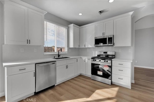 kitchen with light countertops, appliances with stainless steel finishes, a sink, and white cabinetry