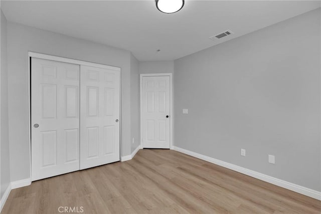 unfurnished bedroom with light wood-style flooring, a closet, visible vents, and baseboards