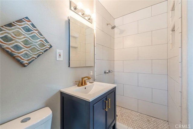 full bath featuring a tile shower, vanity, and toilet