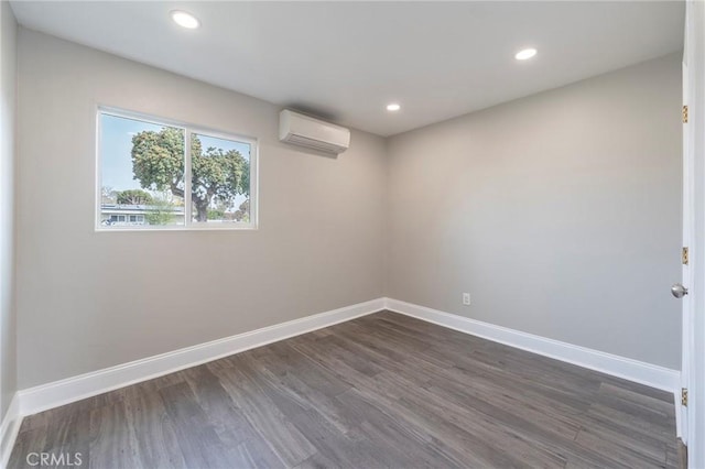 empty room with dark wood-type flooring, a wall unit AC, recessed lighting, and baseboards