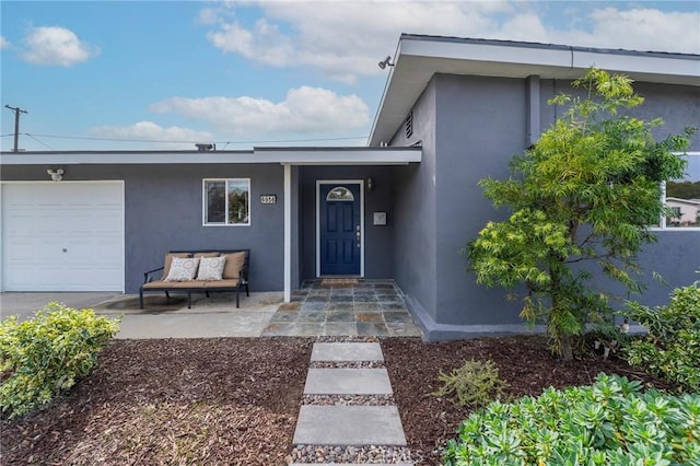 view of exterior entry with a garage and stucco siding