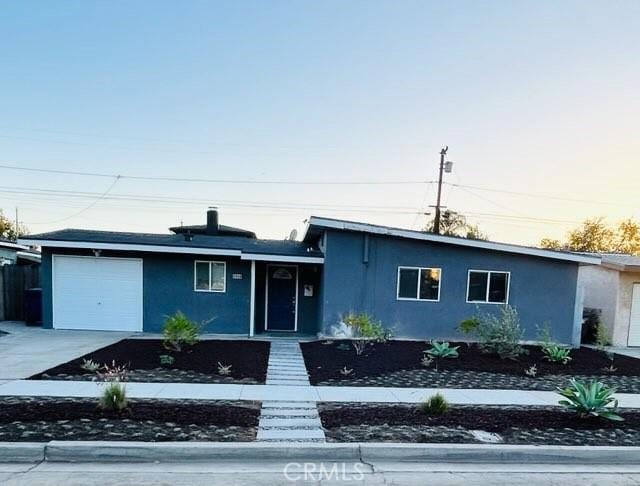 view of front of property with a garage, concrete driveway, and stucco siding