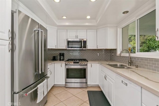 kitchen featuring a raised ceiling, stainless steel appliances, a sink, and white cabinets